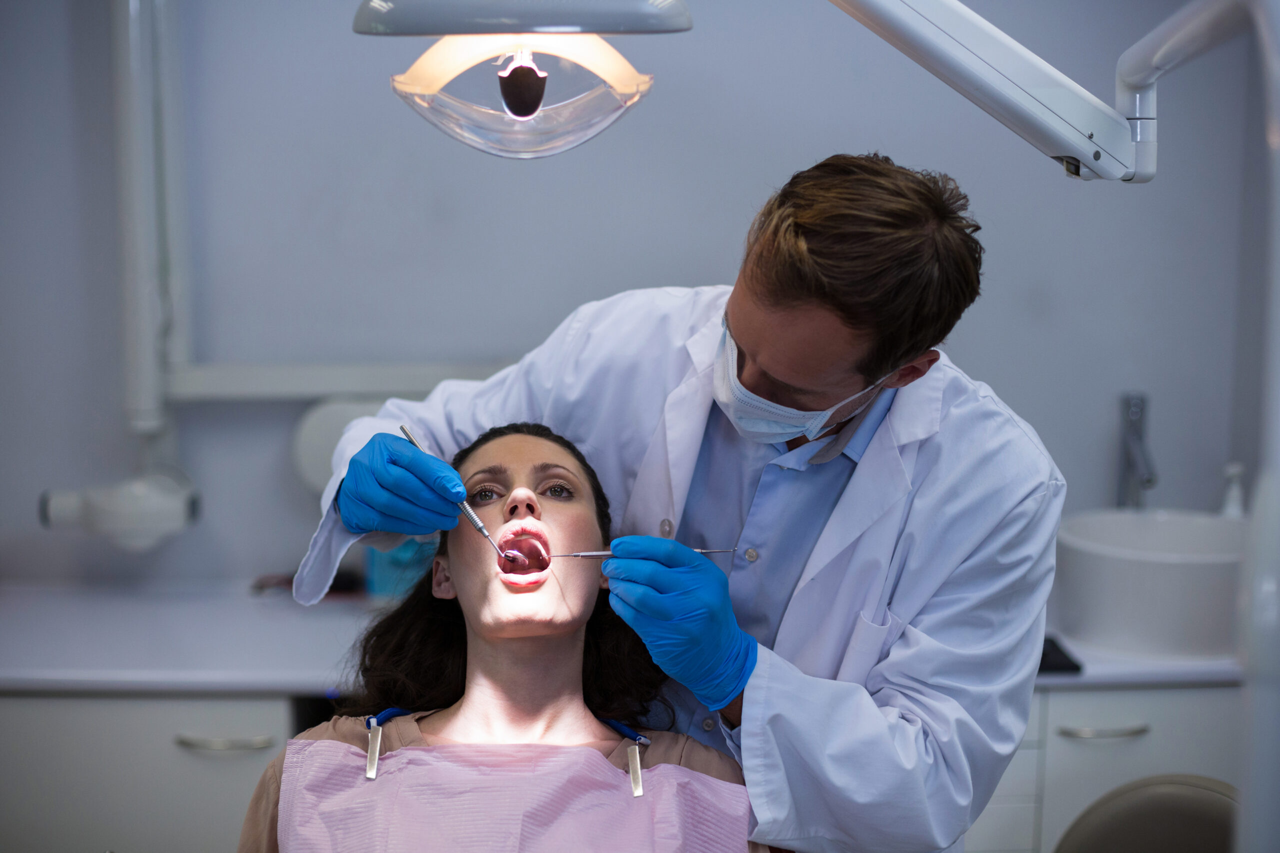 Dentist examining a female patient with tools