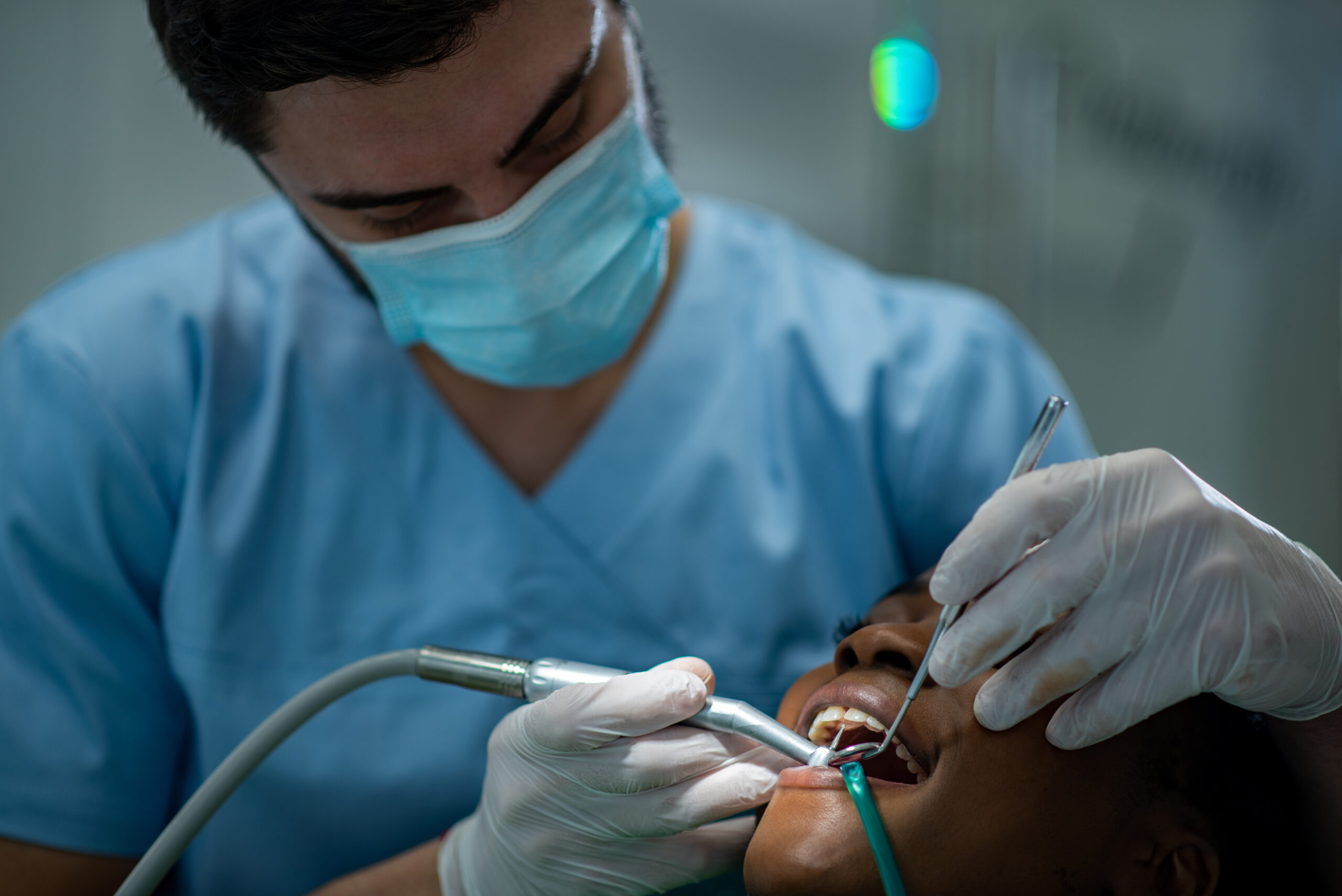 Dentist providing dental care treatment to a african american fe
